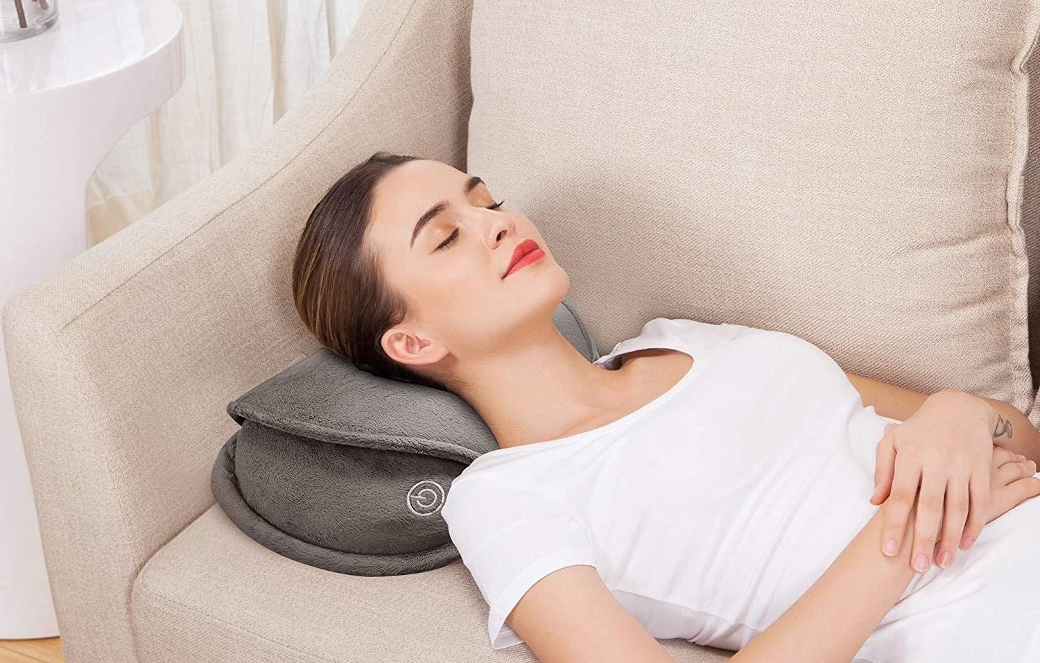 A person lying on a couch using the massage pillow