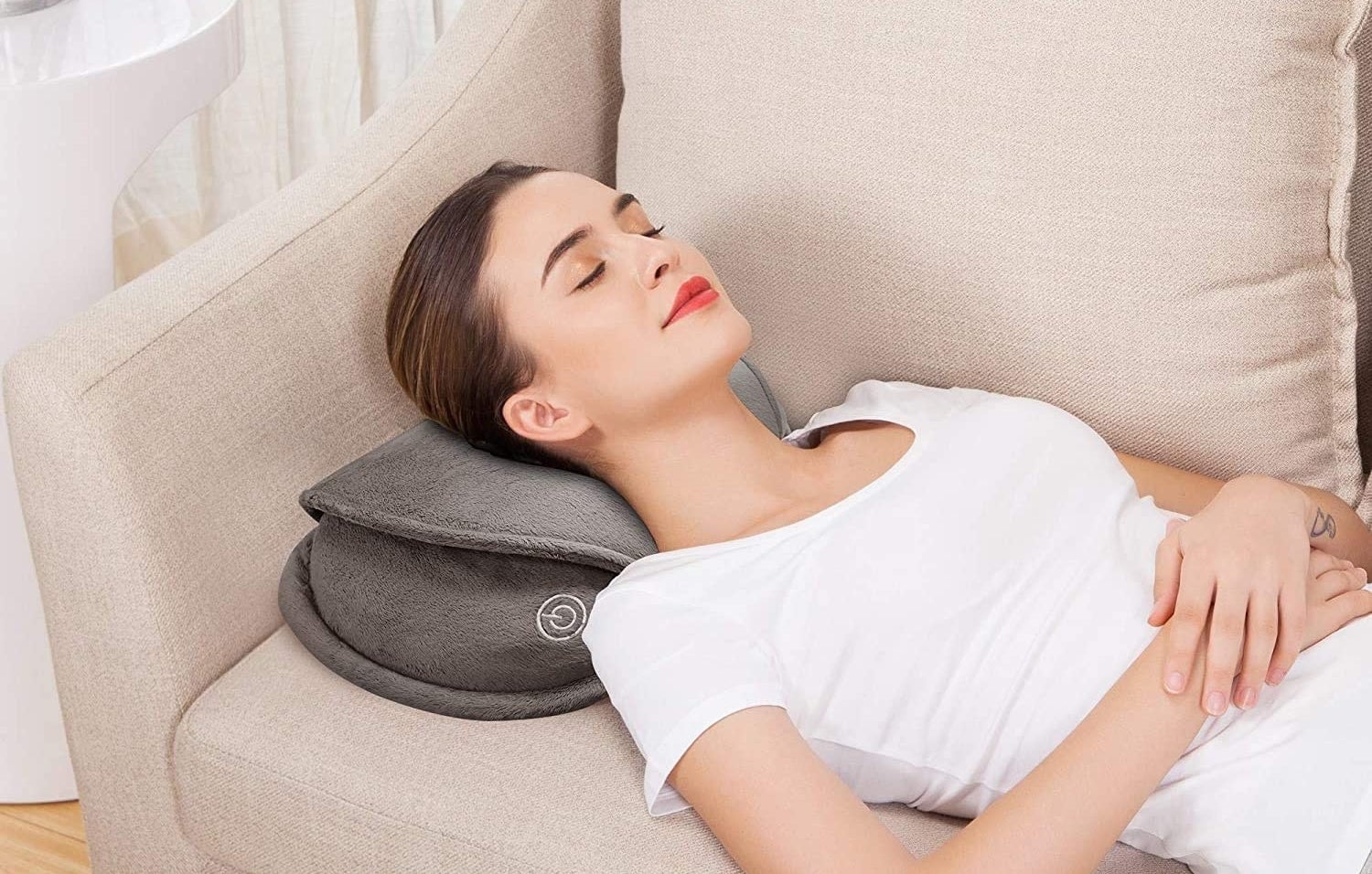 A person lying on a couch using the massage pillow