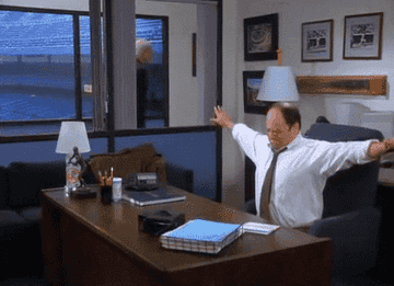 Gif of Jason Alexander on the TV show &quot;Seinfeld&quot; stretching his arms and crawling under his desk to take a nap