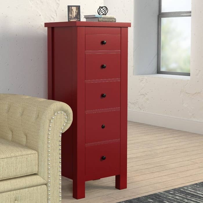 A deep red five-drawer chest with round black knobs