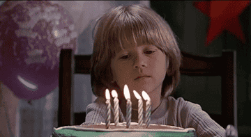 Gif of little boy looking at a birthday cake and making a wish 