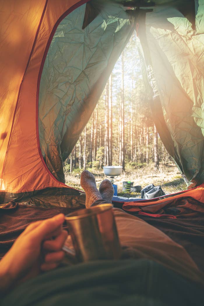 Man relaxing in tent after hike with cup of tea