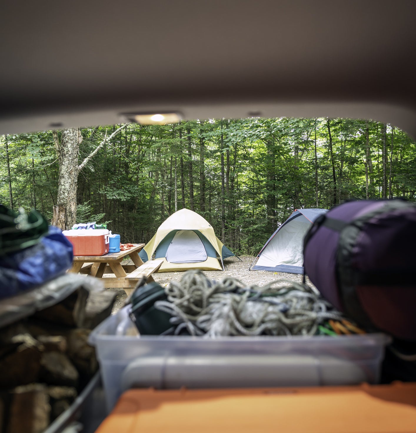 一个装满露营装备的后备箱，背景是一个帐篷
