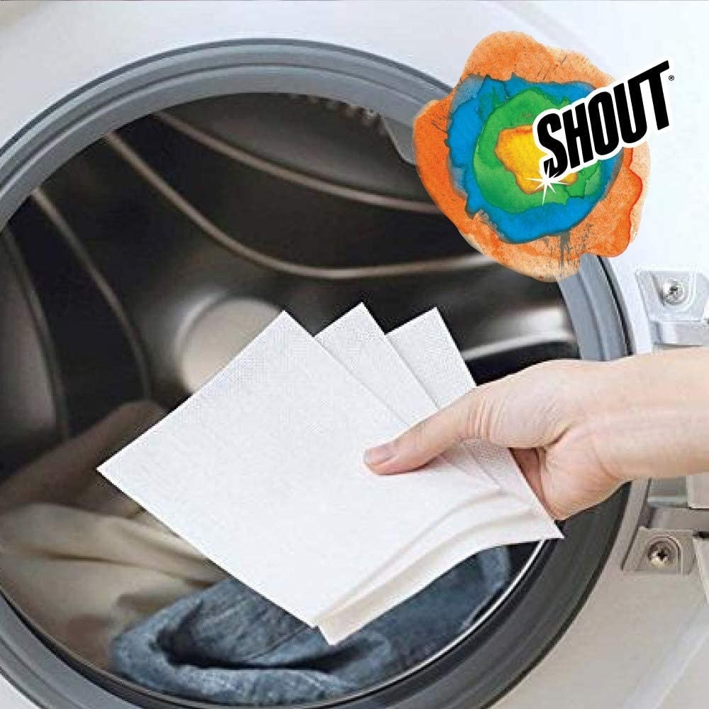 A person placing three fabric sheets into the washing machine