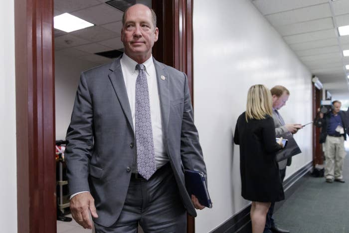 Ted Yoho wears a suit and tie as he carries an iPad while walking out of a door on Capitol Hill in a 2017 photograph.