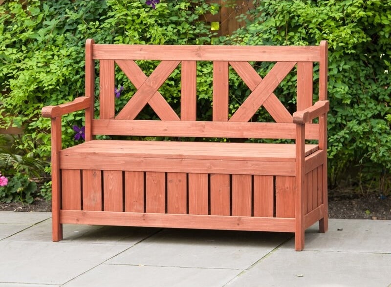A reddish natural wood grain storage bench with arm rests and back