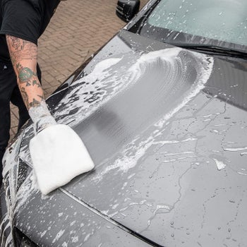 Hand washing a car hood with the mitt