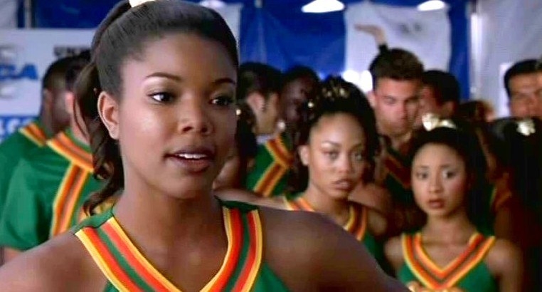 Isis talking to Torrance at the cheerleading competition, wearing her uniform, with a determined expression on her face