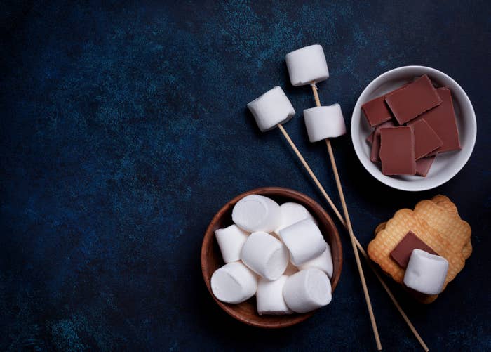 S&#x27;mores ingredients including marshmallows, chocolate, graham crackers, and skewers.