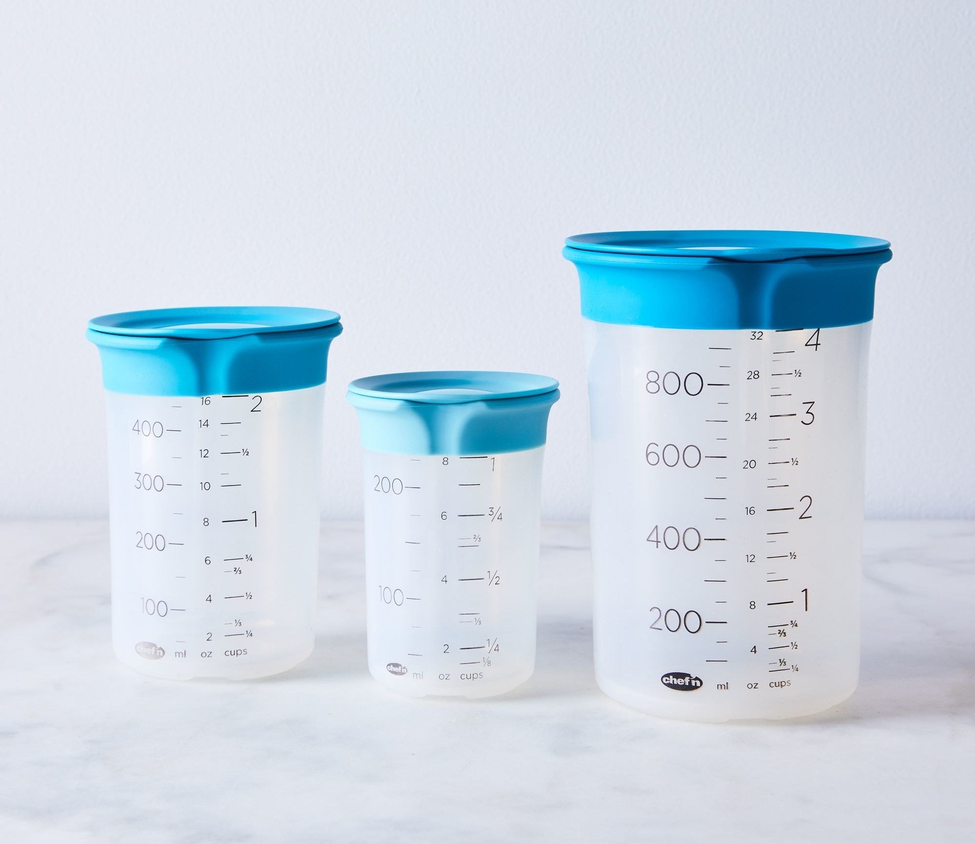 three different size plastic measuring cups with spouts and blue lids
