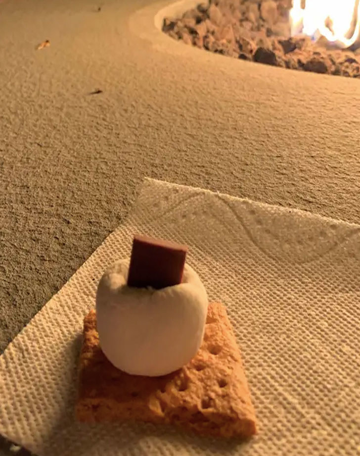 A chocolate square inside a marshmallow on top of a graham cracker.