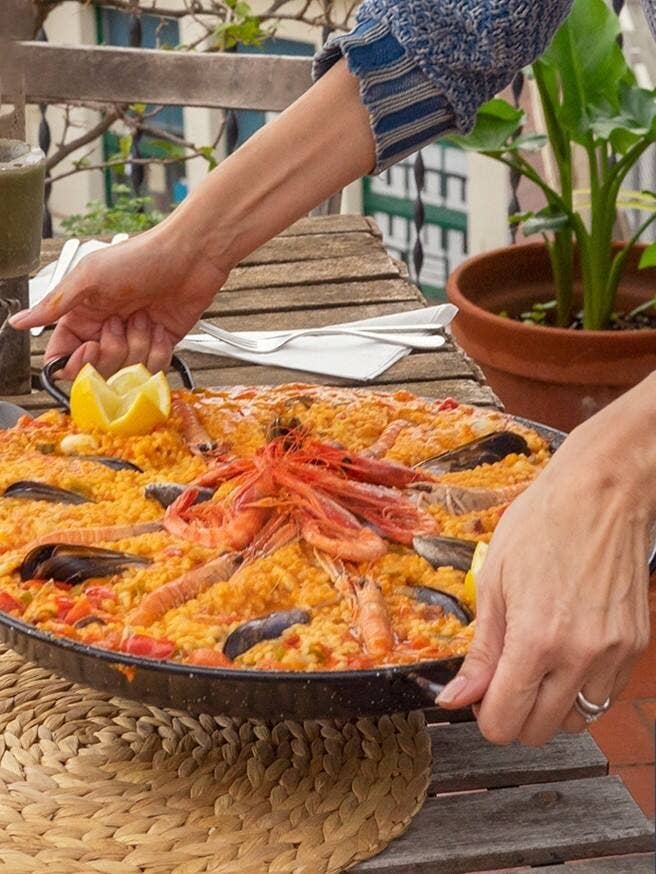 huge pot of seafood paella being places on a table