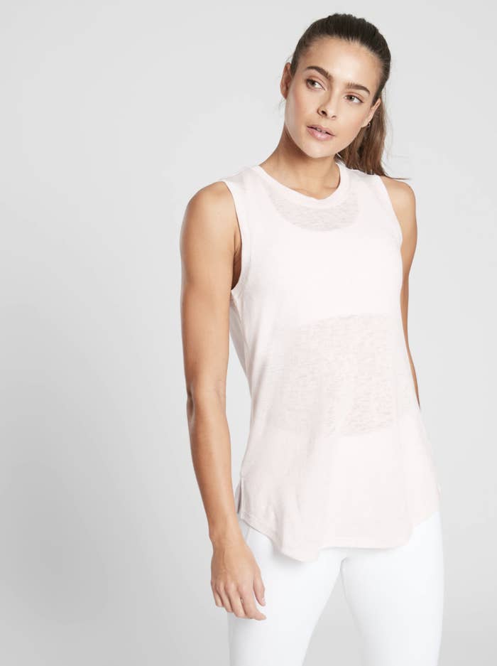 A model wearing a light colored tank top with a loose fit