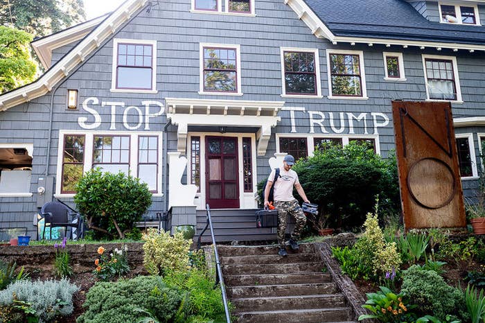 Man walks down the stairs of a house with the words &quot;stop Trump&quot; painted on it.