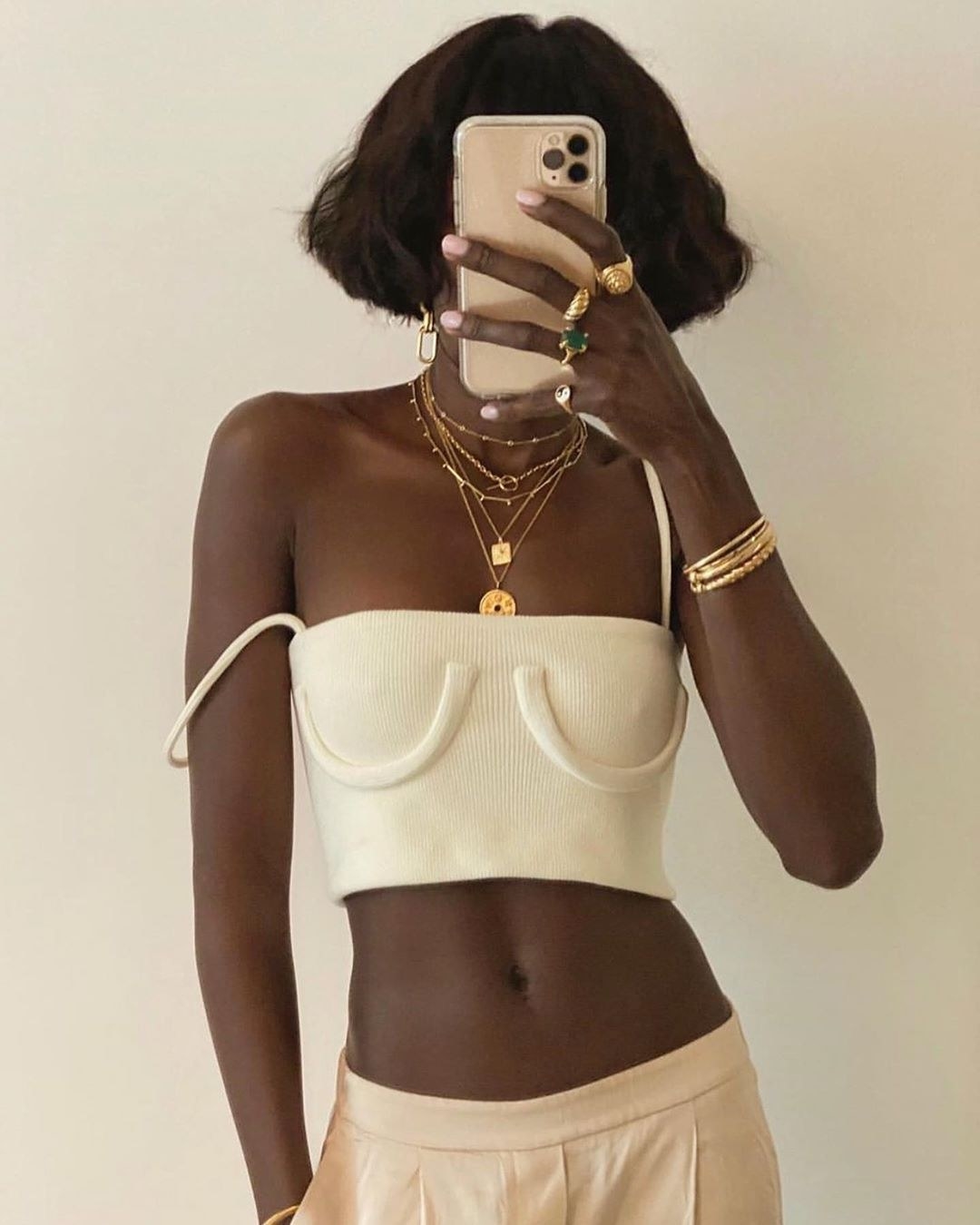 model wears white tank with u-shaped tubes of fabric that look like breasts 