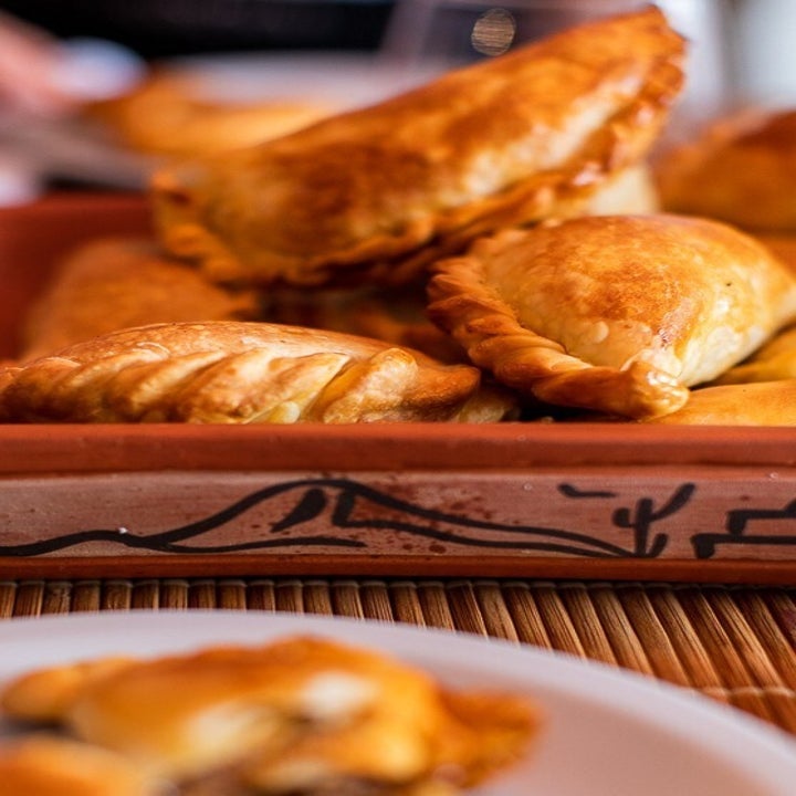 A plate full of golden brown baked empanadas 