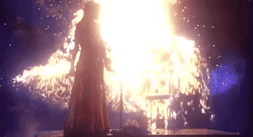Carrie covered in blood on stage as a huge wall of fire surrounds her