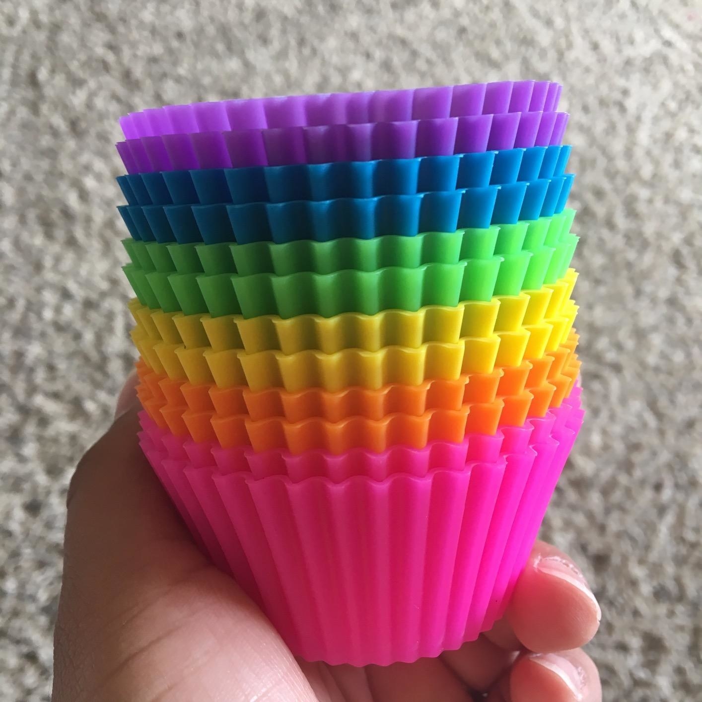 A reviewer&#x27;s hand holding a stack of multi-colored cupcake liners