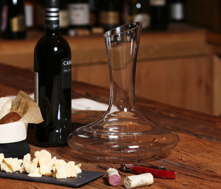 A decanter next to a cheese board and a bottle of wine