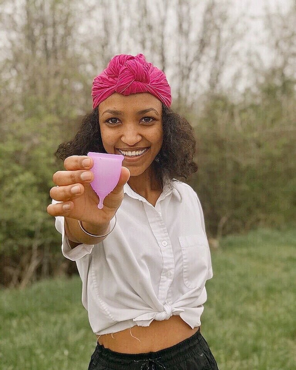 A smiling person holding out the menstrual cup