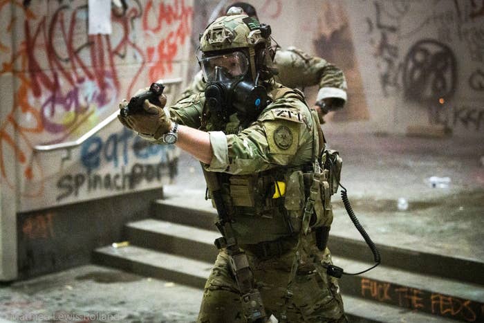 An armed soldier points his pistol at protesters.