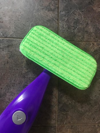 A reviewer's photo of a purple mop handle with the green cleaning pad attached