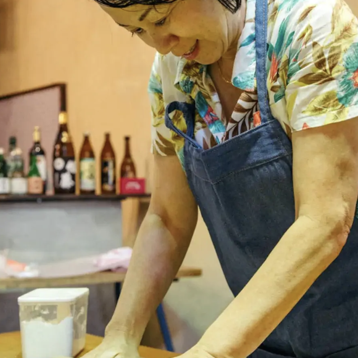 woman rolling dough to make udon noodles