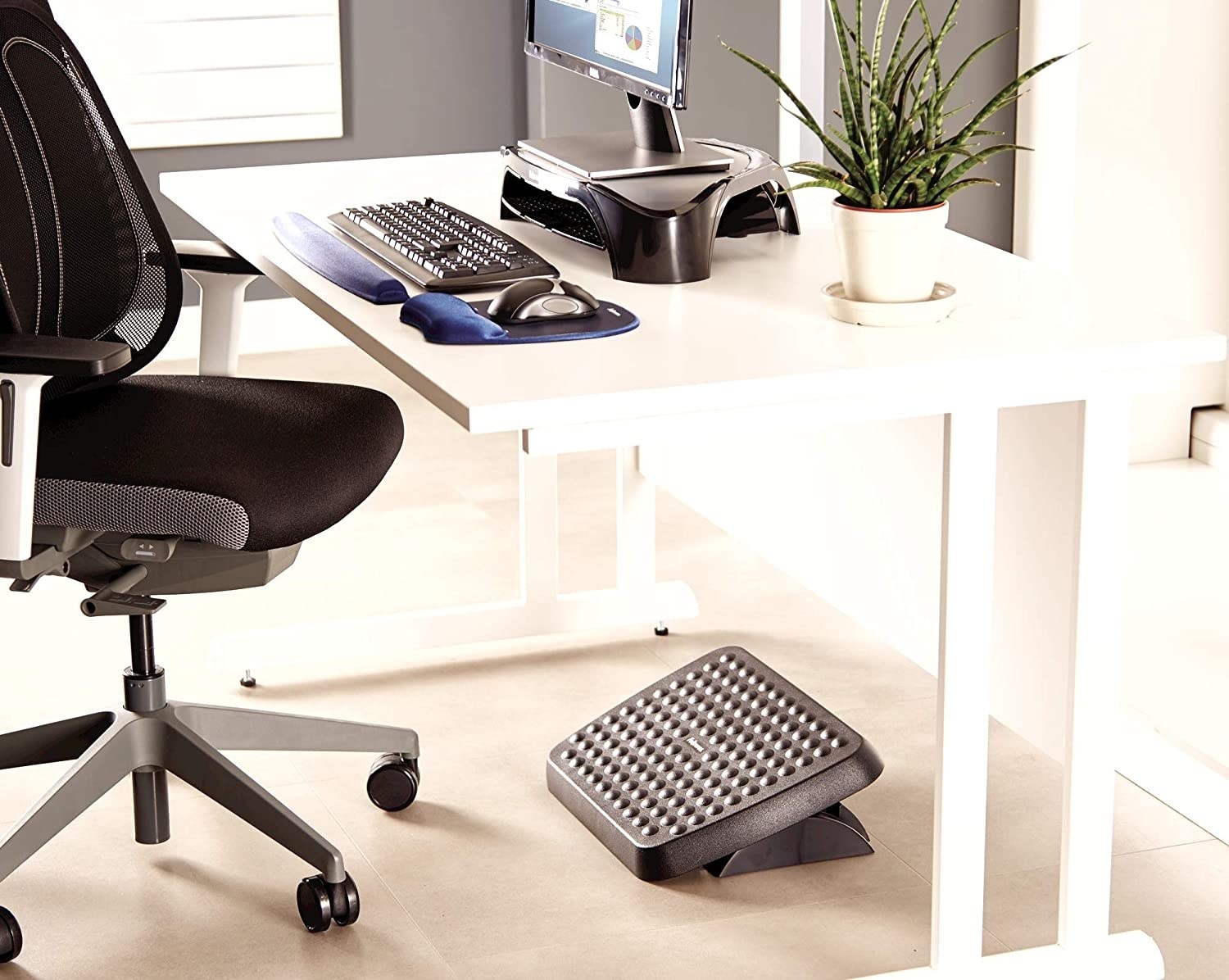 An angled foot rest under a desk with office equipment