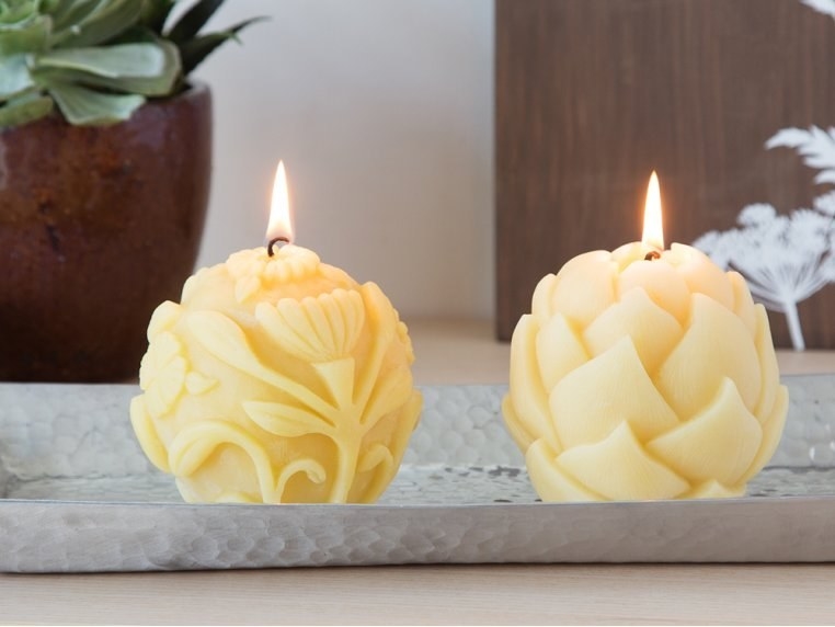 Two of the candles in different carved designs — one floral and one with layered petals
