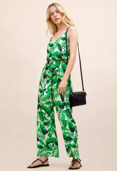 a model in a green leaf covered jumpsuit