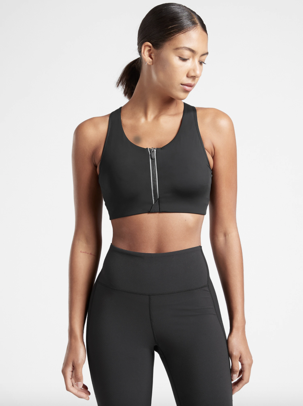 A model wearing the u-neck sports bra, which has a zippered front