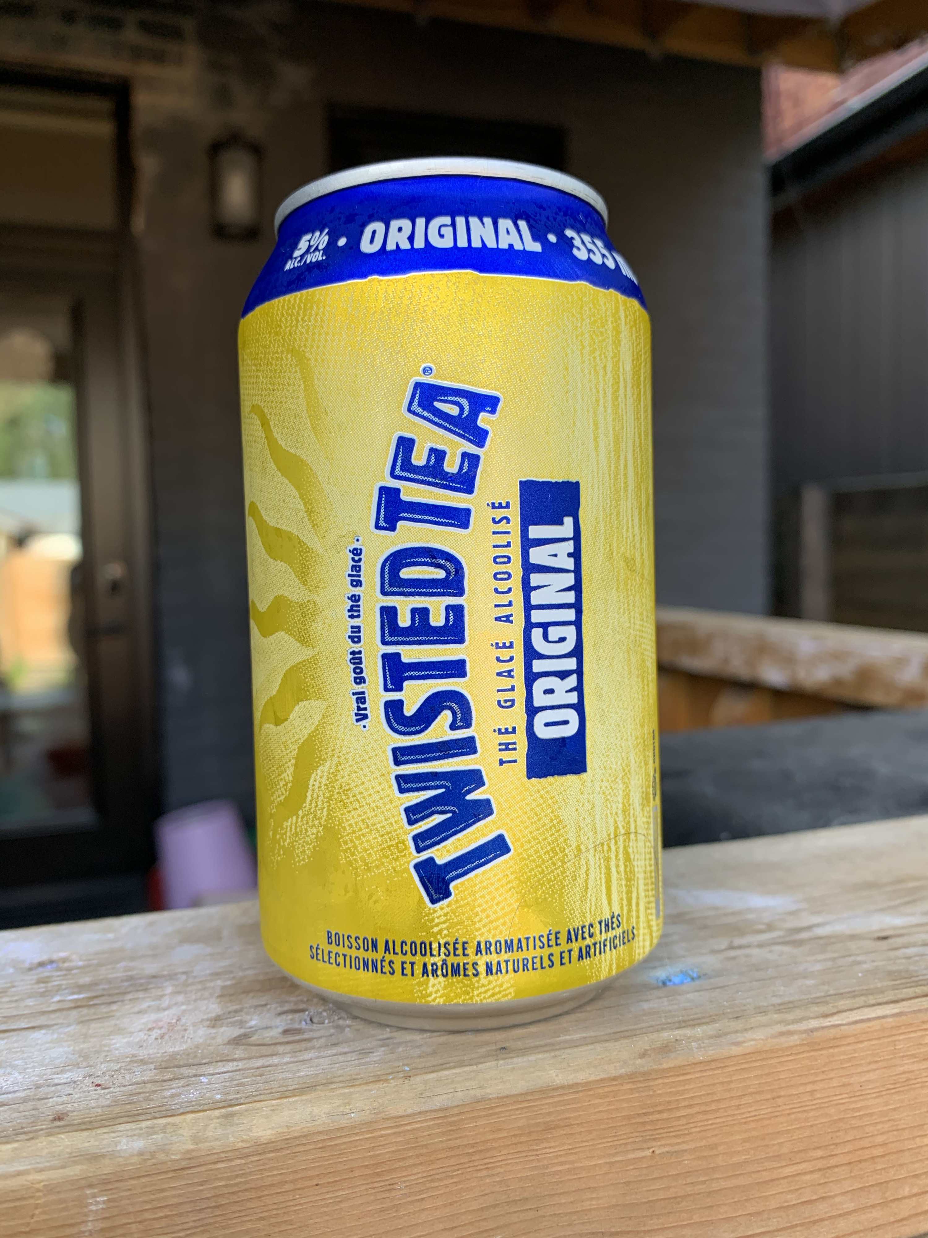 A yellow and blue can of Twisted Tea that says &quot;original&quot; on the can in blue and white. There&#x27;s a sun burst peaking out on the background.