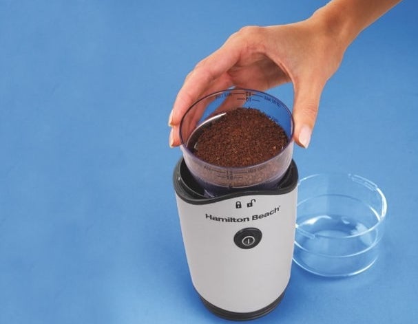The grinder filled with ground coffee beans 