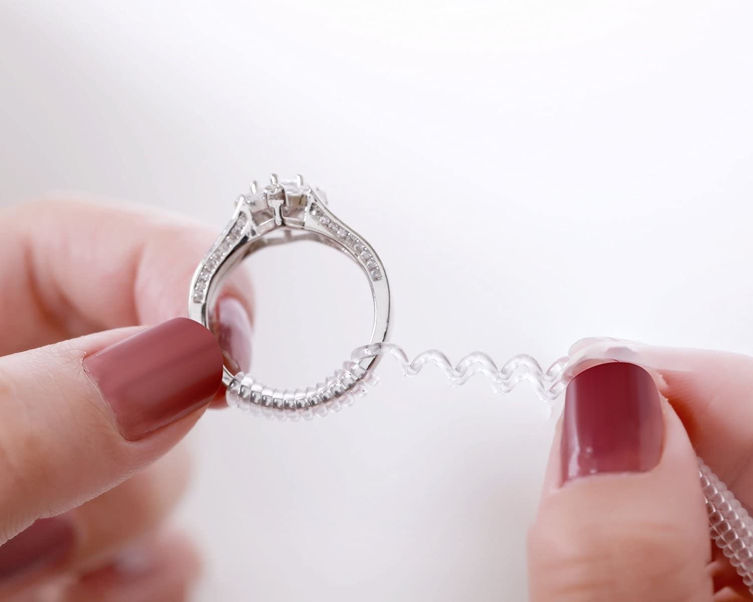 A person putting the ring adjuster onto a diamond ring