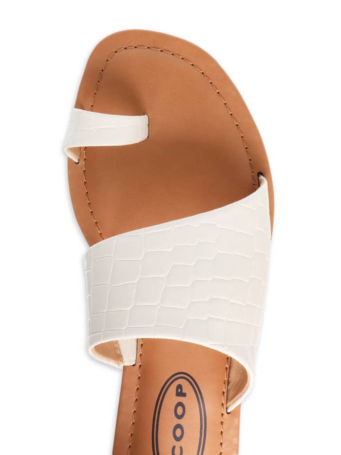 A top-down view of a white toe-ring sandal with a tan leather insole