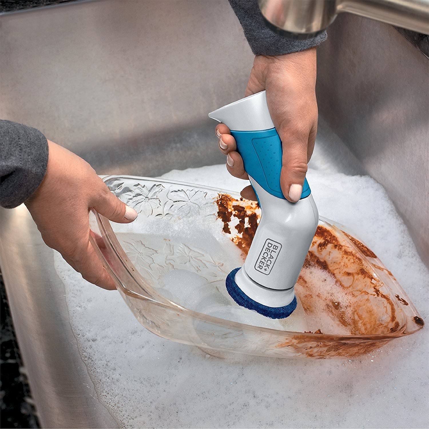 Hand scrubbing dirty pan with power scrubber 