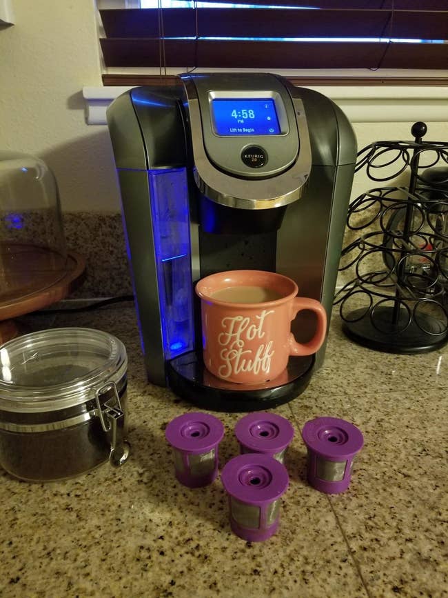 A reviewer's photo of four purple K-cups in front of a Keurig