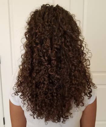 Reviewer with sleek curly hair after using the conditioning set