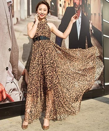 A model wearing the dress in leopard print with a belt around the waist