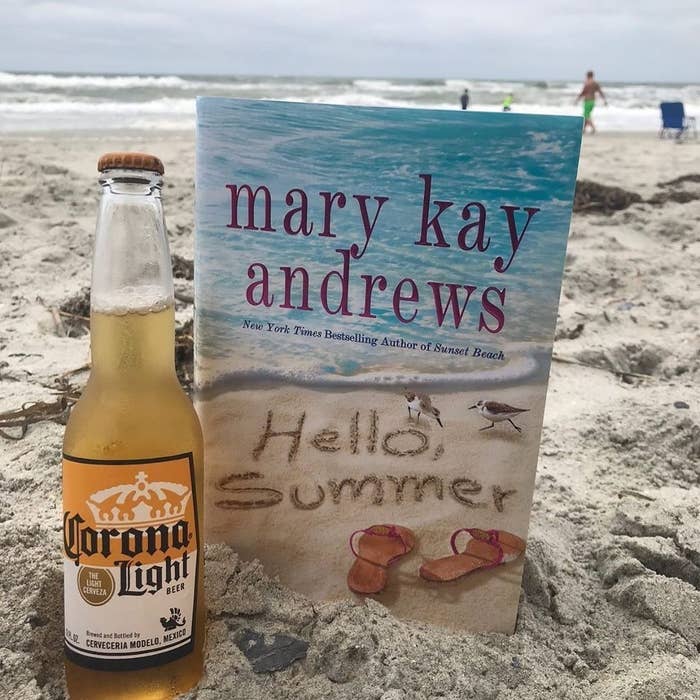 The book propped up in the sand with a beer