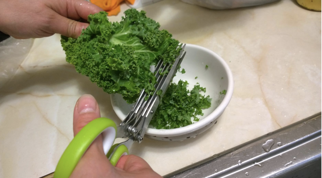 A reviewer chopping kale into a bowl 