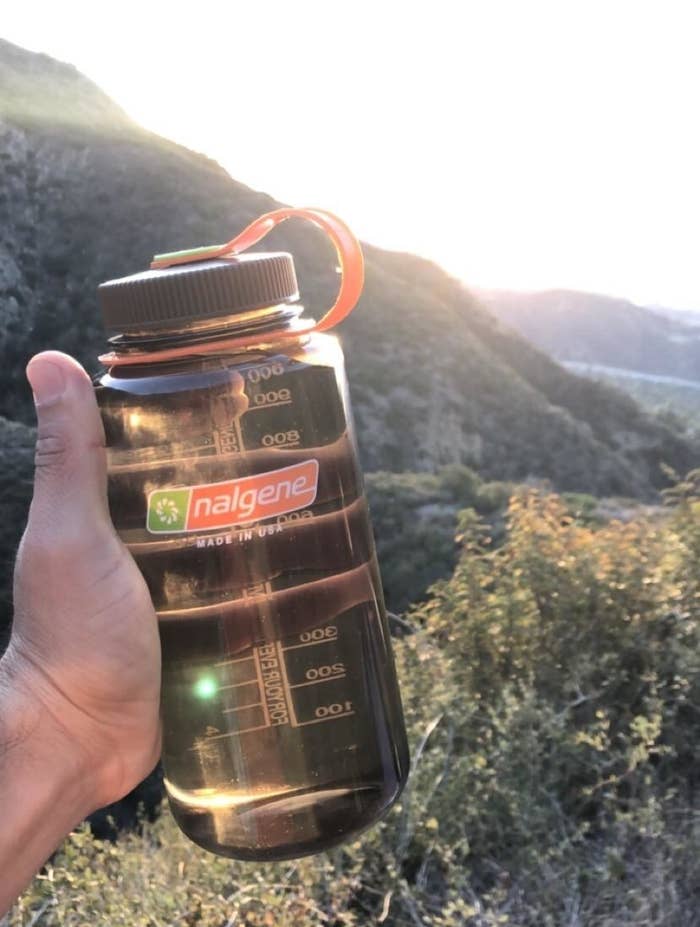 Reviewer holding their water bottle while hiking 