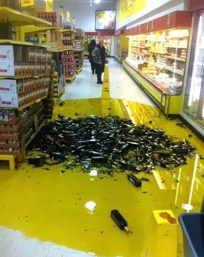 A grocery aisle with dozens of broken bottles of olive oil.