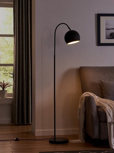 A black floor lamp with a rounded cover 