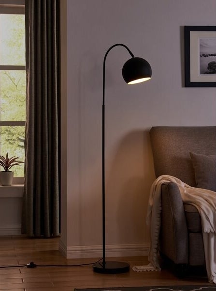 A black floor lamp with a rounded cover