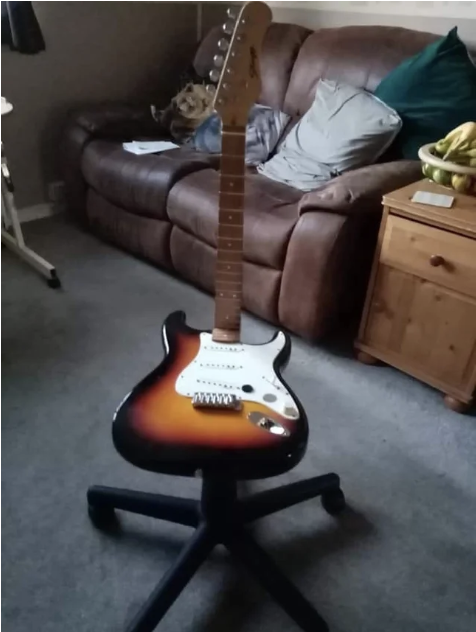 A stool made out a guitar where the neck of the guitar is the backrest
