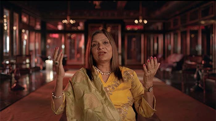 Sima Taparia from &quot;Indian Matchmaking&quot; in a talking head confessional while wearing a yellow sari. 