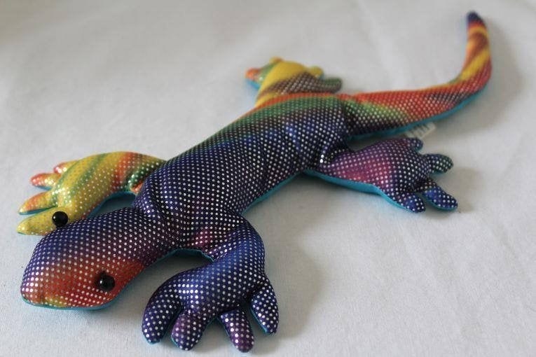 A photo of a stuffed lizard made with a rainbow-colored iridescent fabric. 