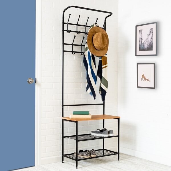 A three shelf storage bench with open shelving for shoes and nine hooks for hanging clothing