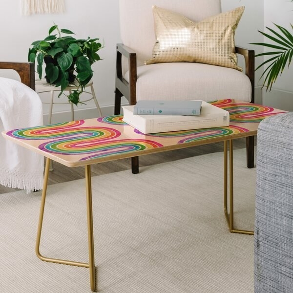 A multicolored coffee table with a simple wood top and folded gold metal legs